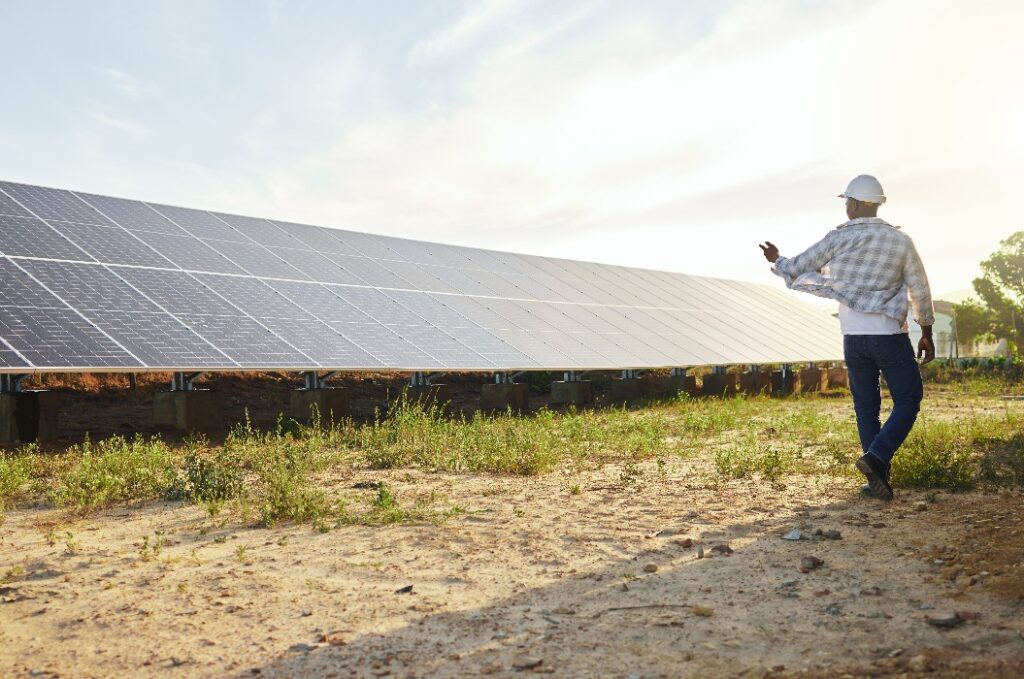 Rücken, Mann und Solarpanel in erneuerbaren Energien für Ökologie, nachhaltige und saubere Energie. Ingenieur, alternativer Generator und kohlenstoffneutrale Technologie für Umweltschutz, Umwelt oder Ökostrom
